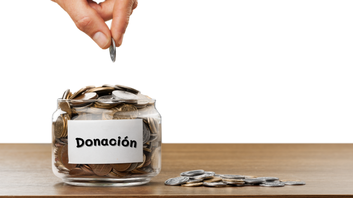 Mano donando moneda en frasco lleno de monedas